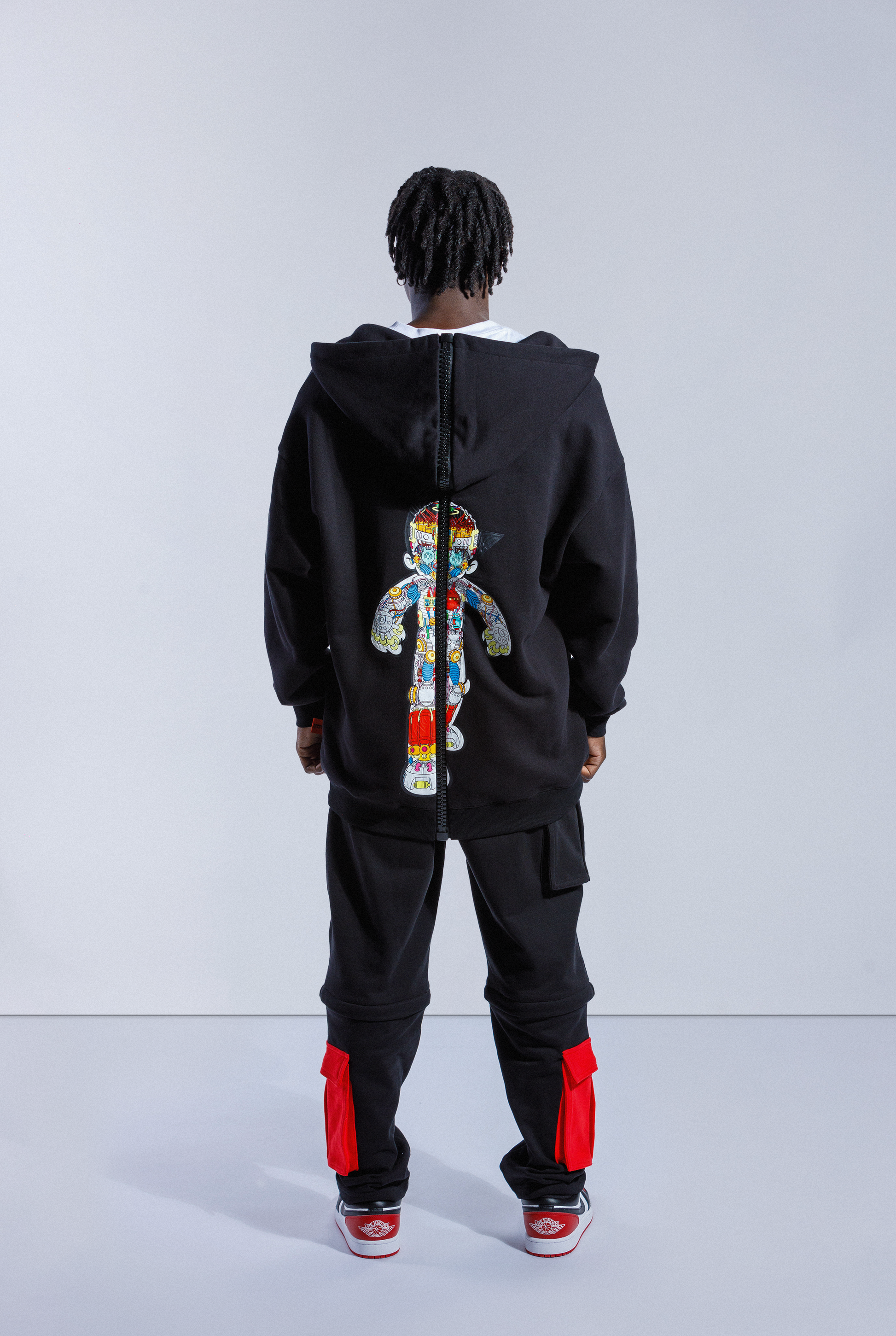 Back of model wearing Black Astro Boy zip hoodie with large black zip down the middle and Astro Boy graphic showing his internal mechanism