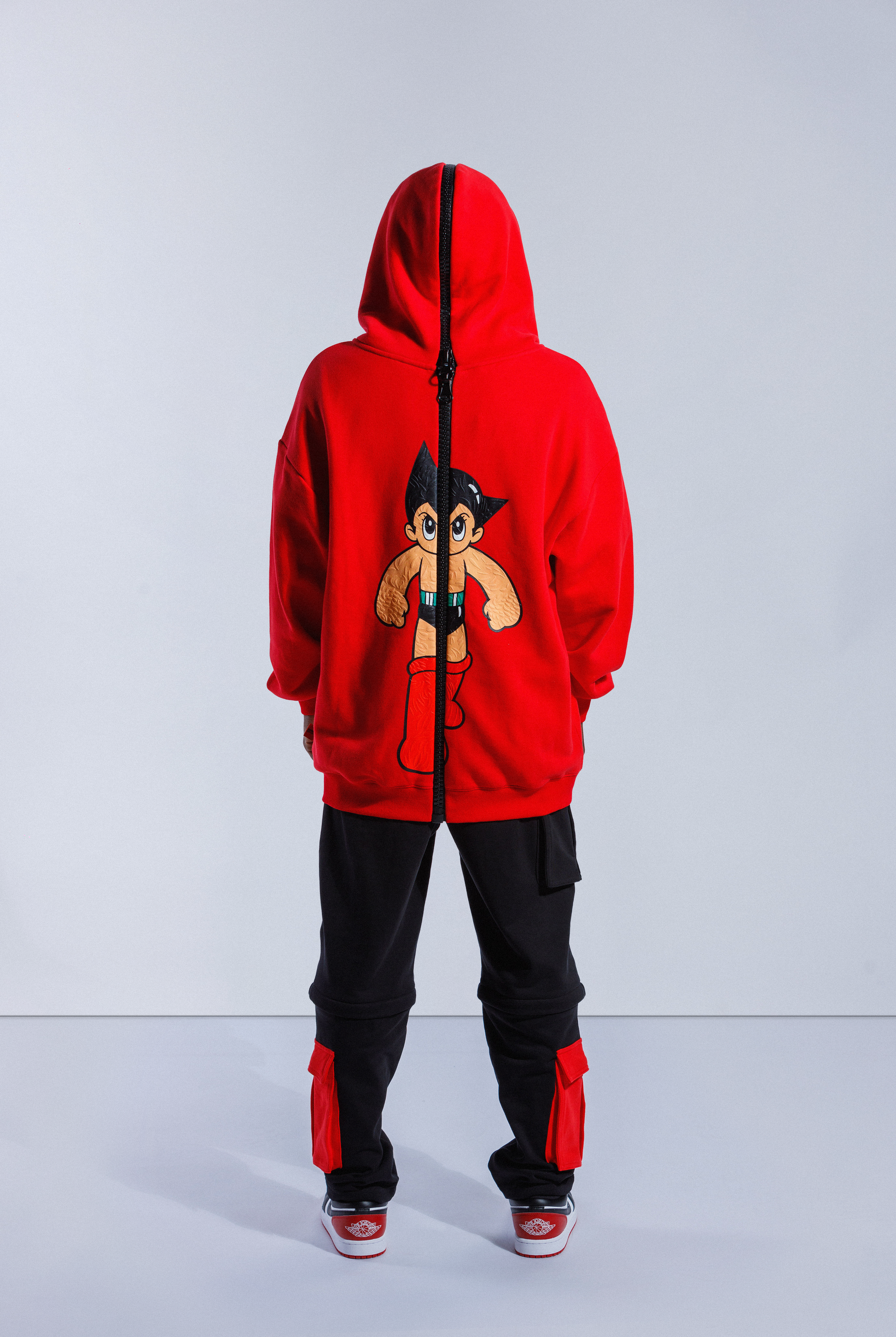 Back of model wearing Red Astro Boy hoodie with large black zip down the middle and hood up