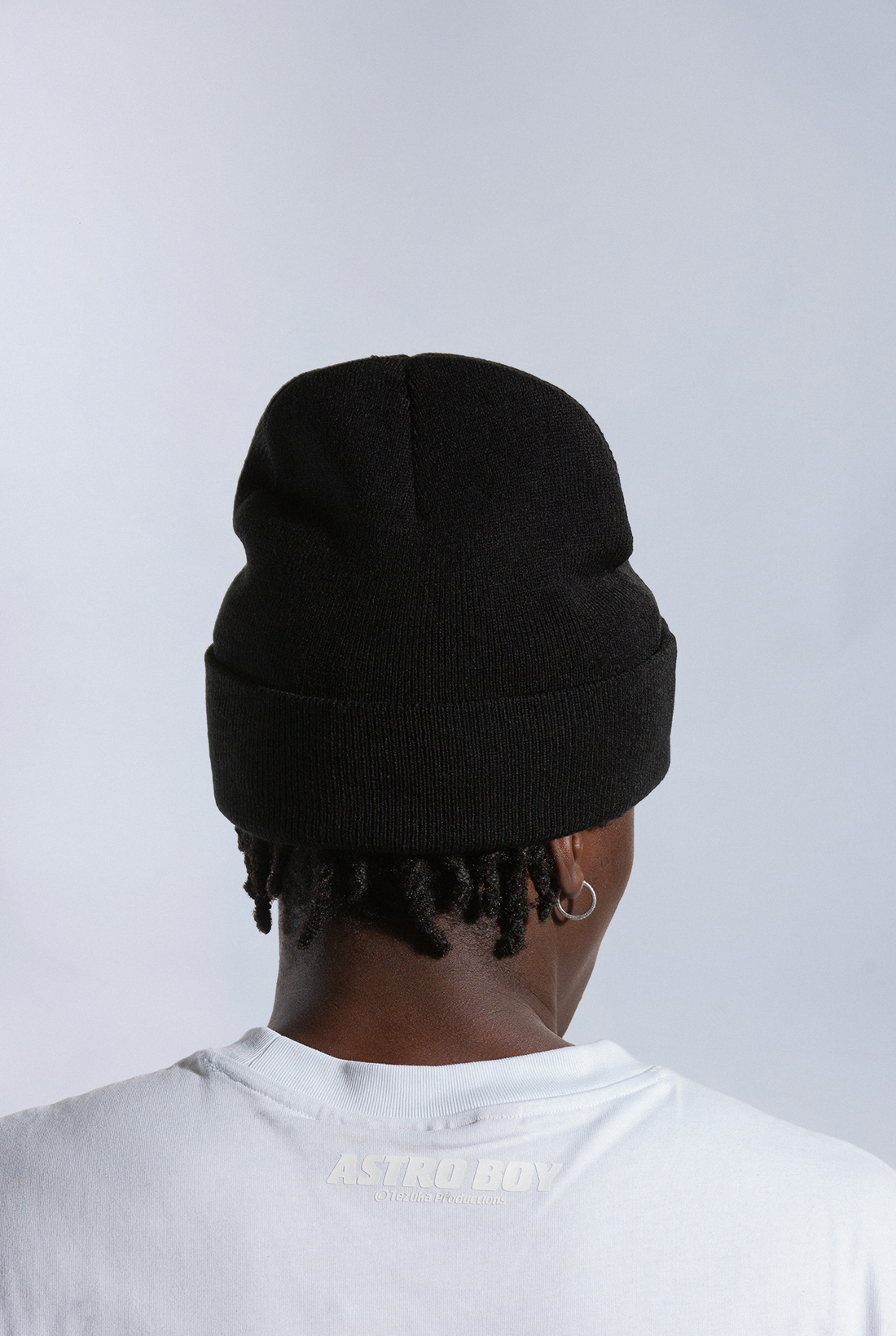 Model wearing black Astro Boy beanie with embroidered Japanese text that reads 'ATOM BOY' - The original Astro Boy Logo