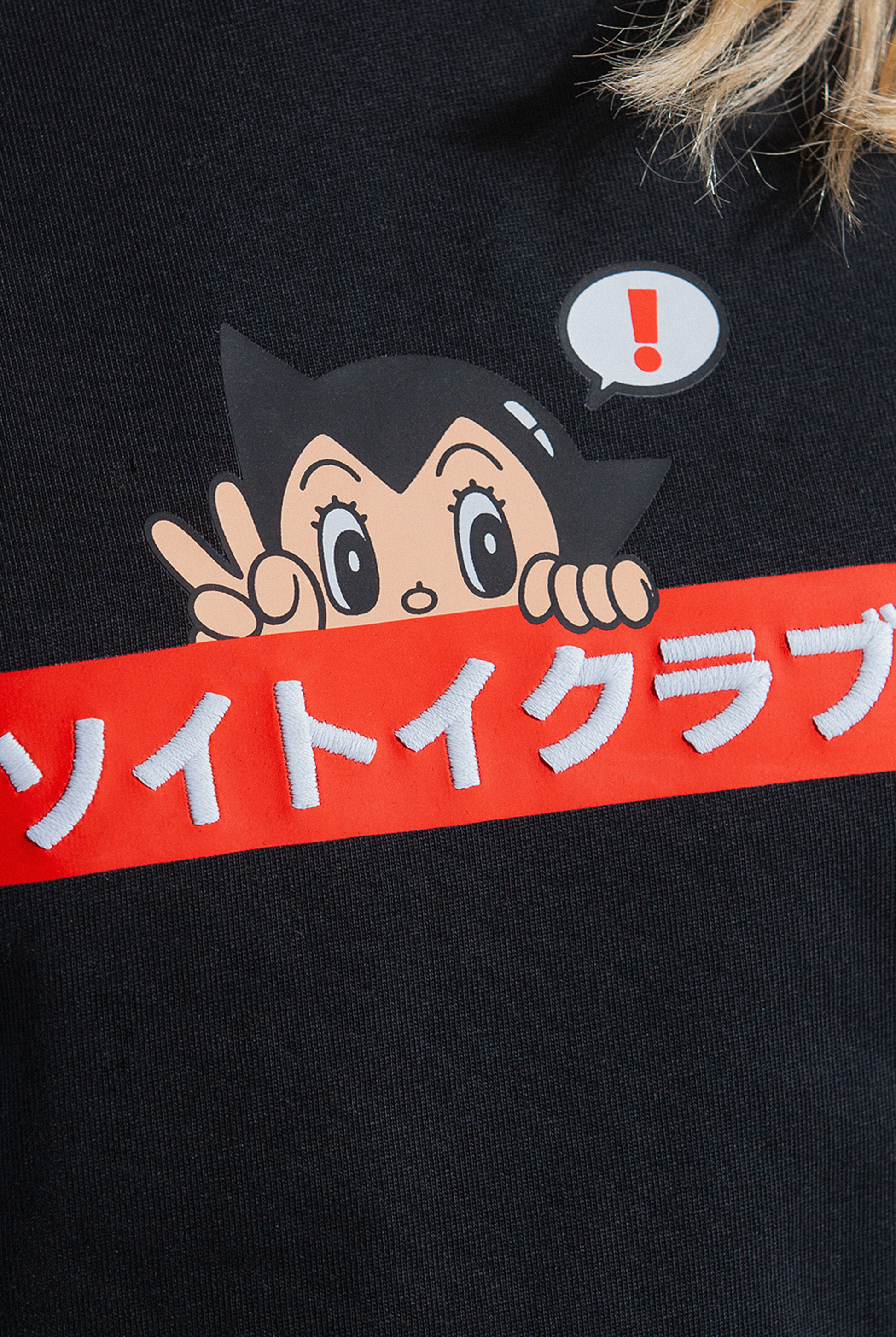 Close up of OG Astro Boy Logo tee. Tee has red box with Japanese 'SOYTOY CLUB' embroidered on the front with Astro Boy on top