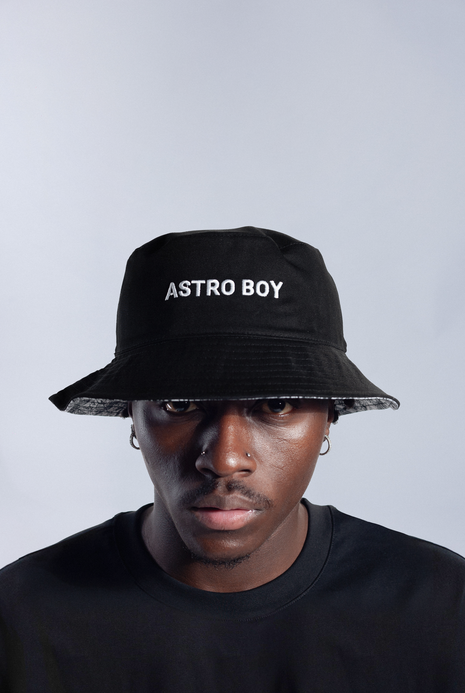 Model wearing reversible Astro Boy bucket hat with black side out that features white text that reads ASTRO BOY