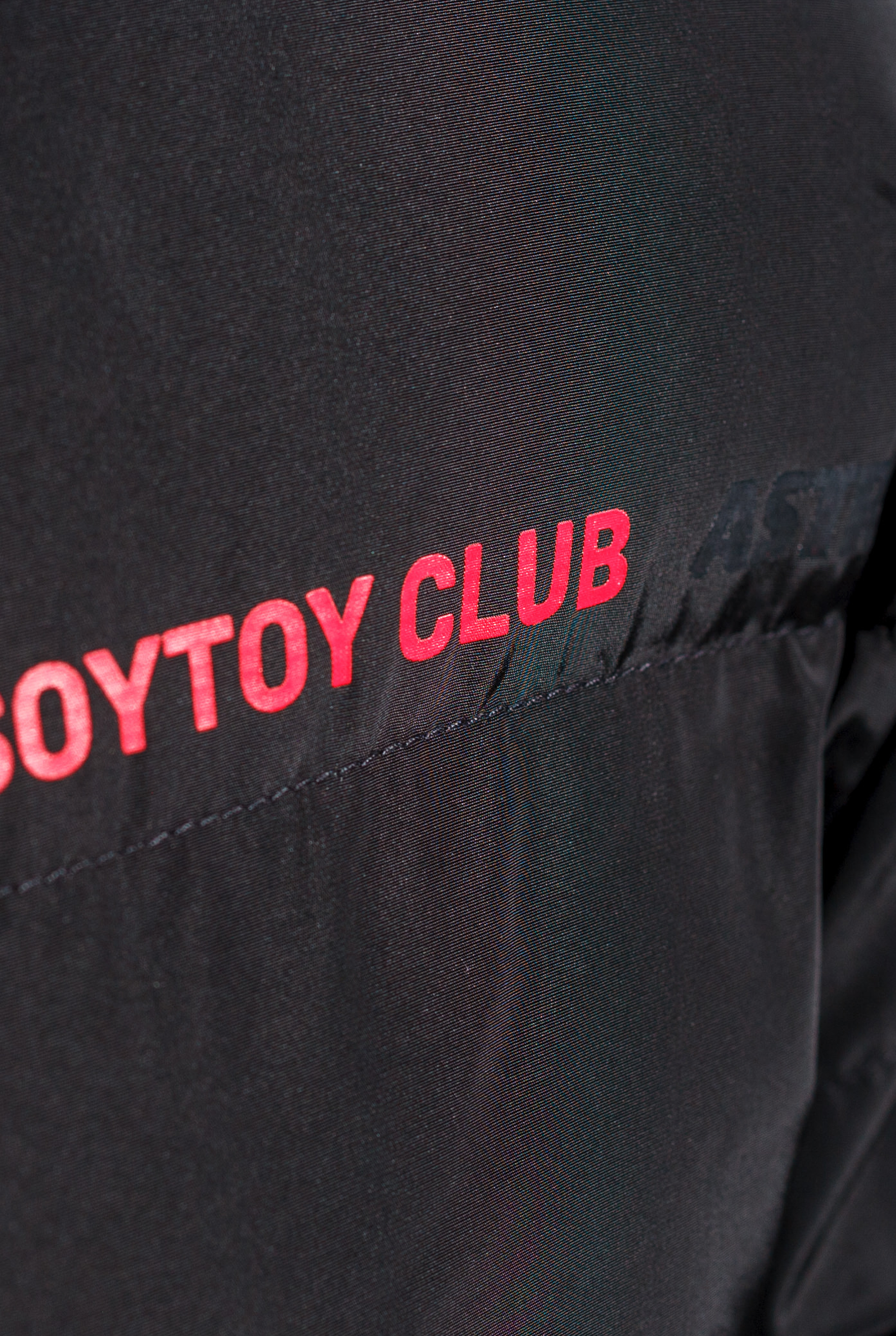 Detail shot of red 'SOYTOY CLUB' text on black puffer jacket