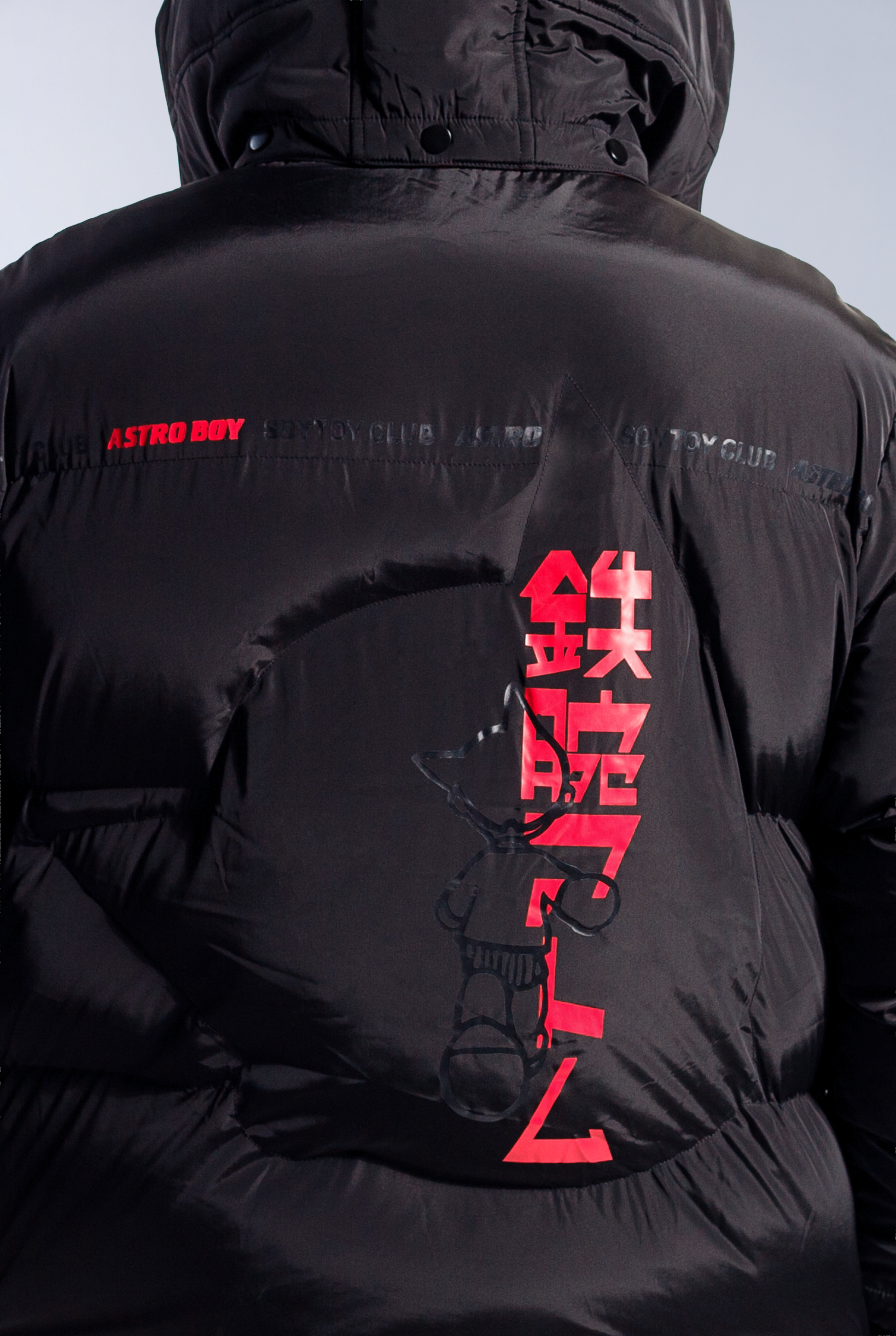 Close up of Astro Boy head silhouette stitched into back of puffer jacket. Also features red and black logo 