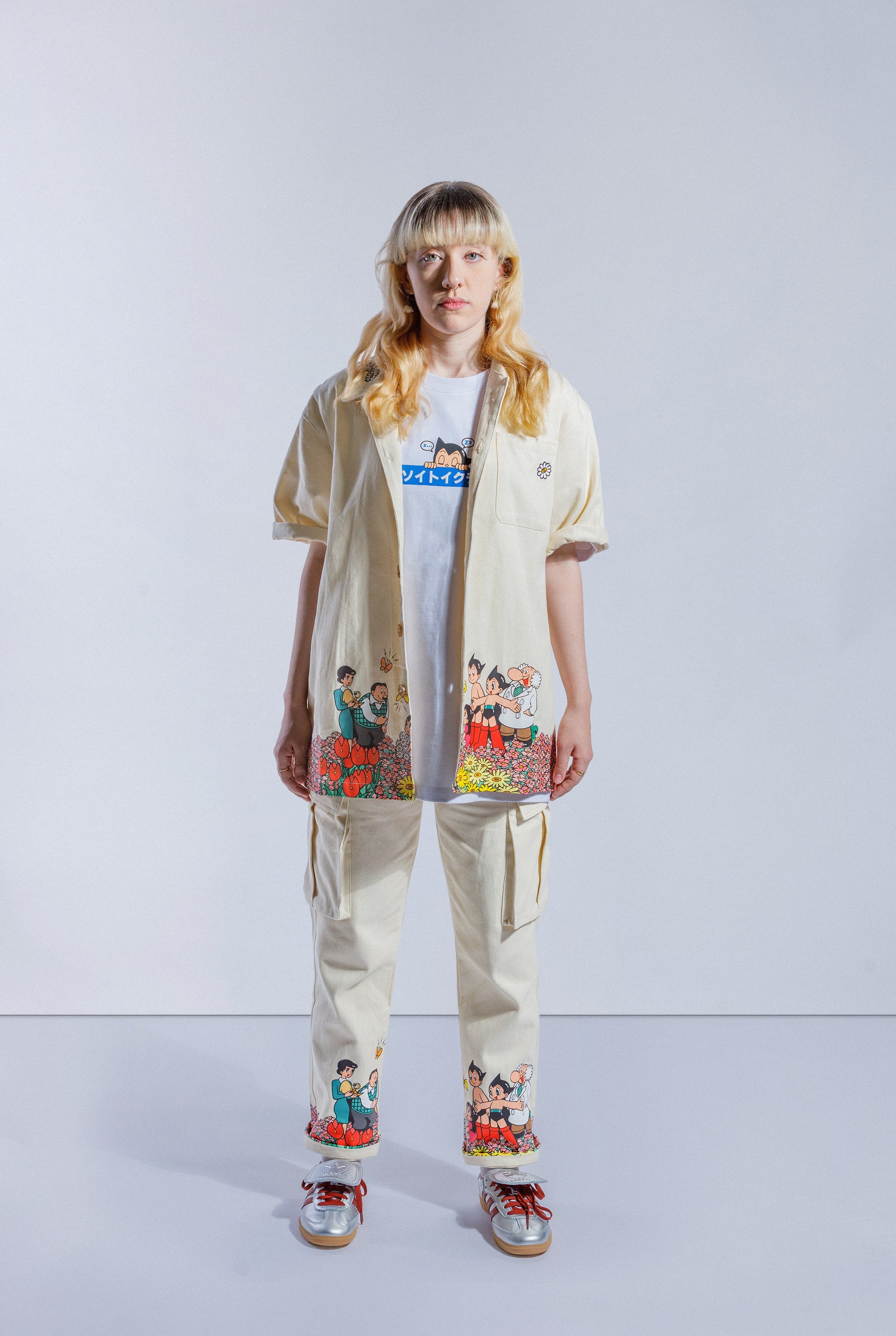 Model wearing cream Astro Boy button up shirt. Features a screen printed graphic that wraps around the bottom shirt. The graphic shows Astro Boy and his family in a field of flowers