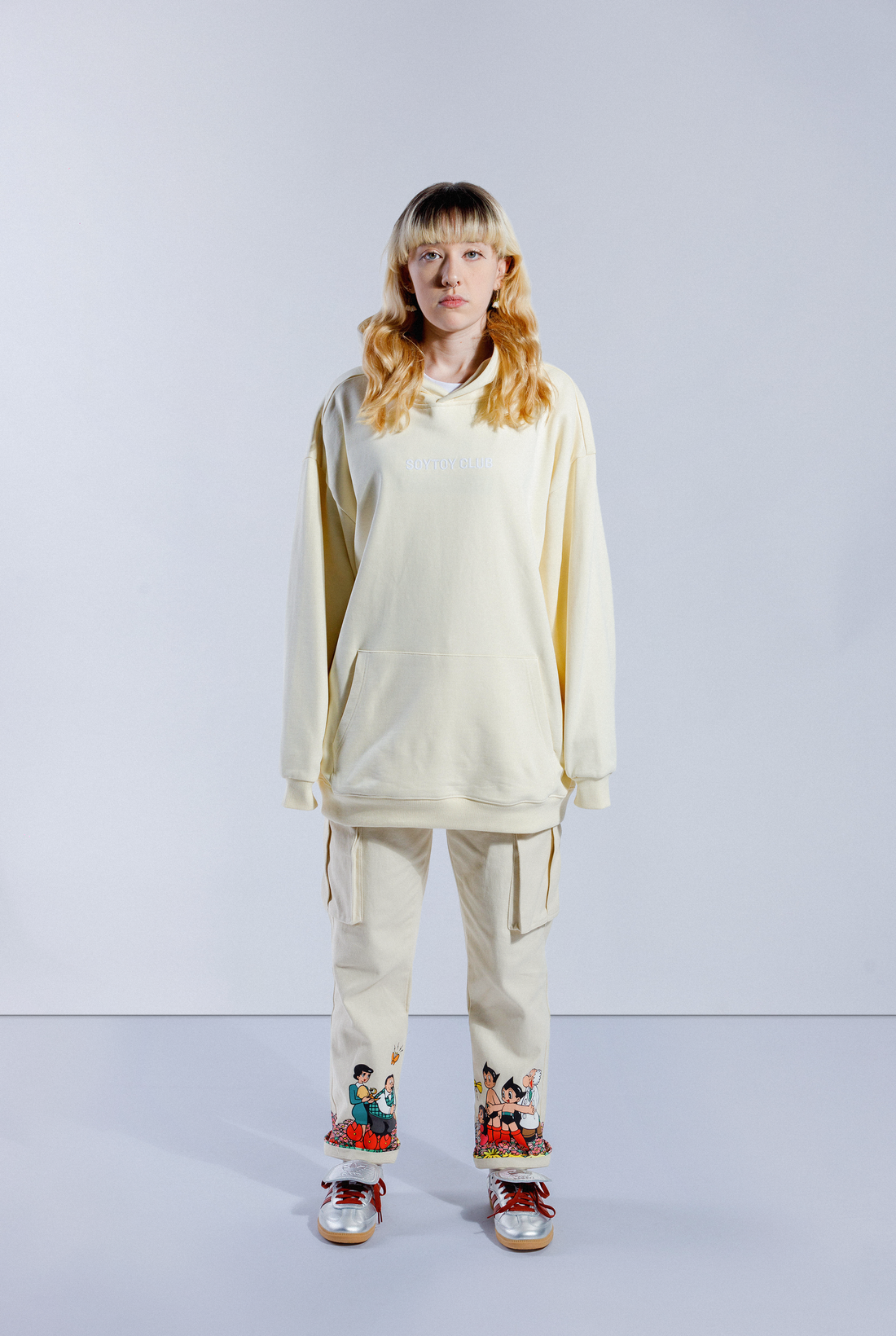 Back of model wearing Sleepy Boi hoodie. Shows large Soytoy Club text with chenille embroidered Astro Boy sleeping in a field of stars