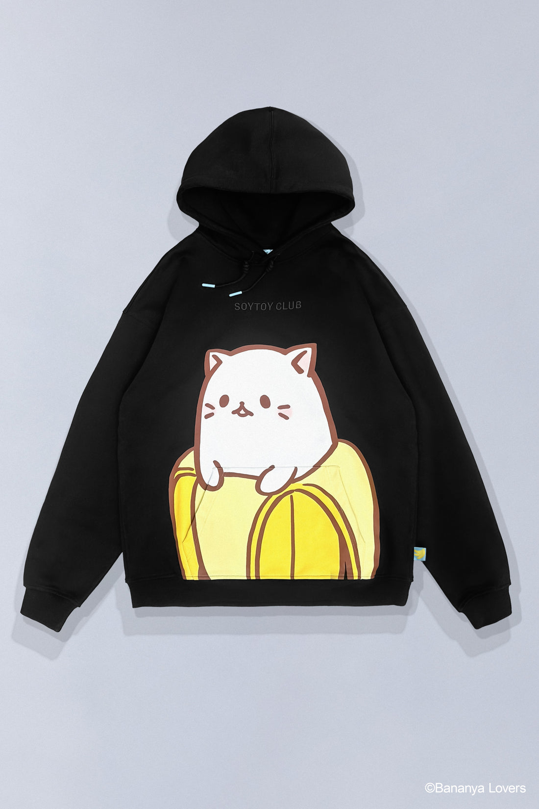 Black SOYTOY CLUB hoodie featuring Bananya the white cartoon cat sitting inside a yellow banana on a light gray background