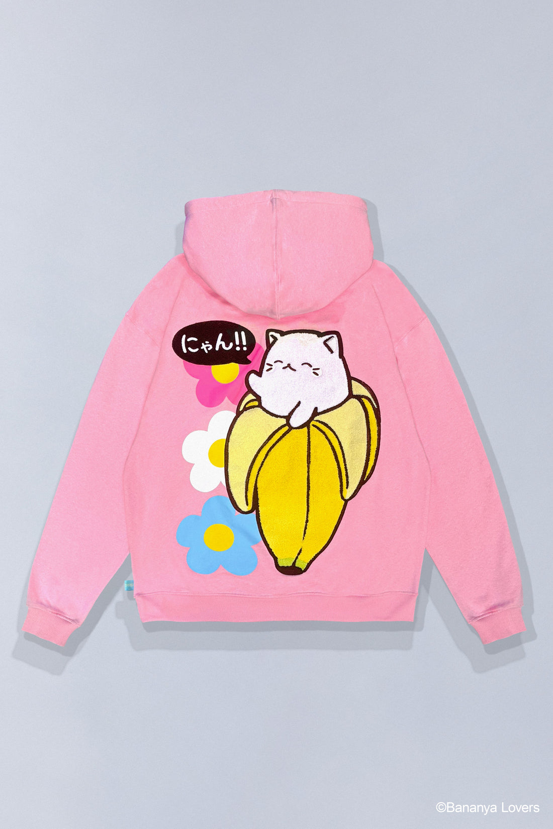 Pink SOYTOY CLUB hoodie featuring embroidered Bananya the white cartoon cat sitting inside a yellow banana on top of  coloured flowers. Hoodie is on a light gray background