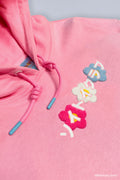 Close-up of pink Bananya SOYTOY CLUB hoodie with embroidered flowers and Japanese text that reads 'soytoy club' 