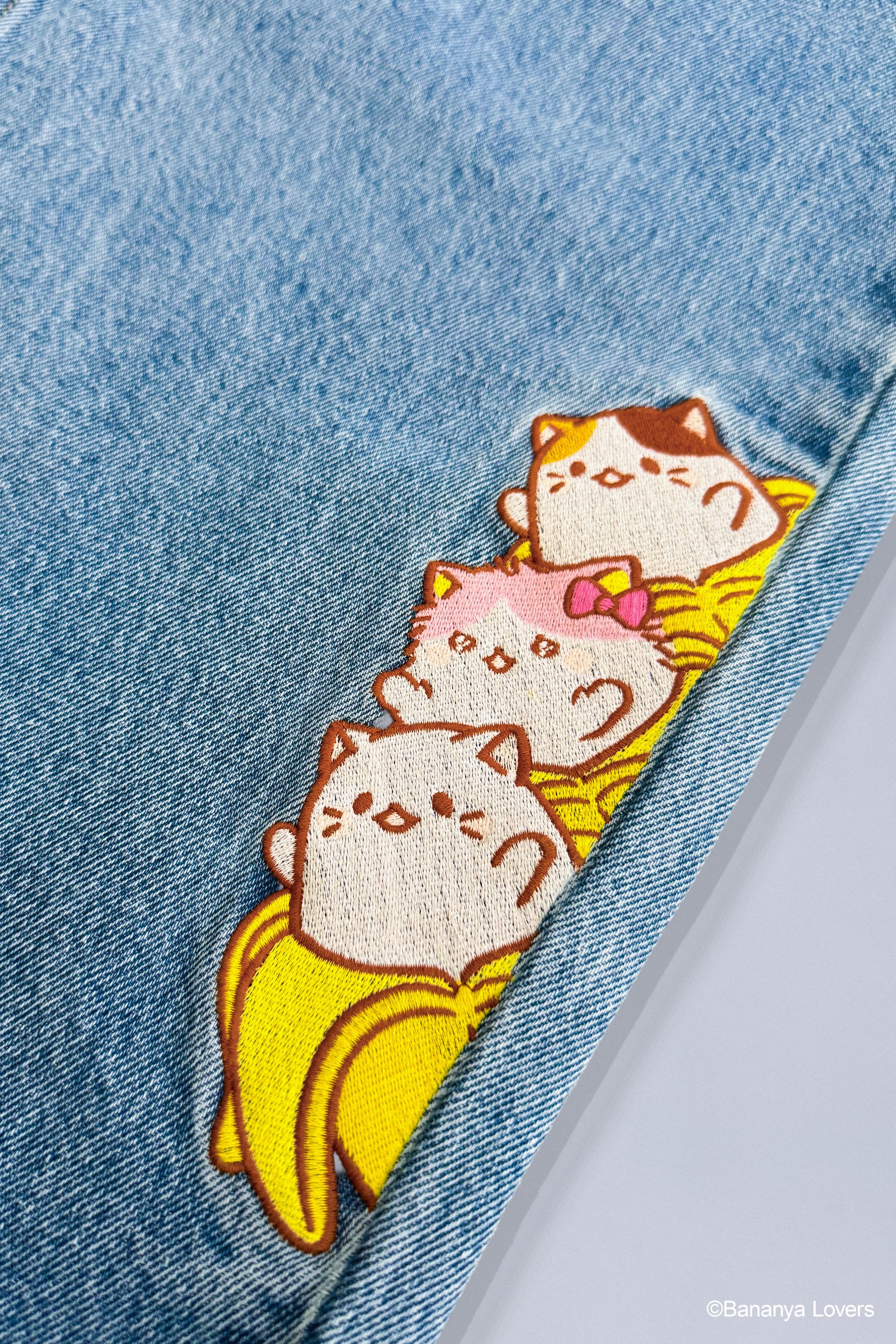 Close up of embroidered detail showing Bananya cat, Bananyako cat and Mike Bananya stacked on top of each other
