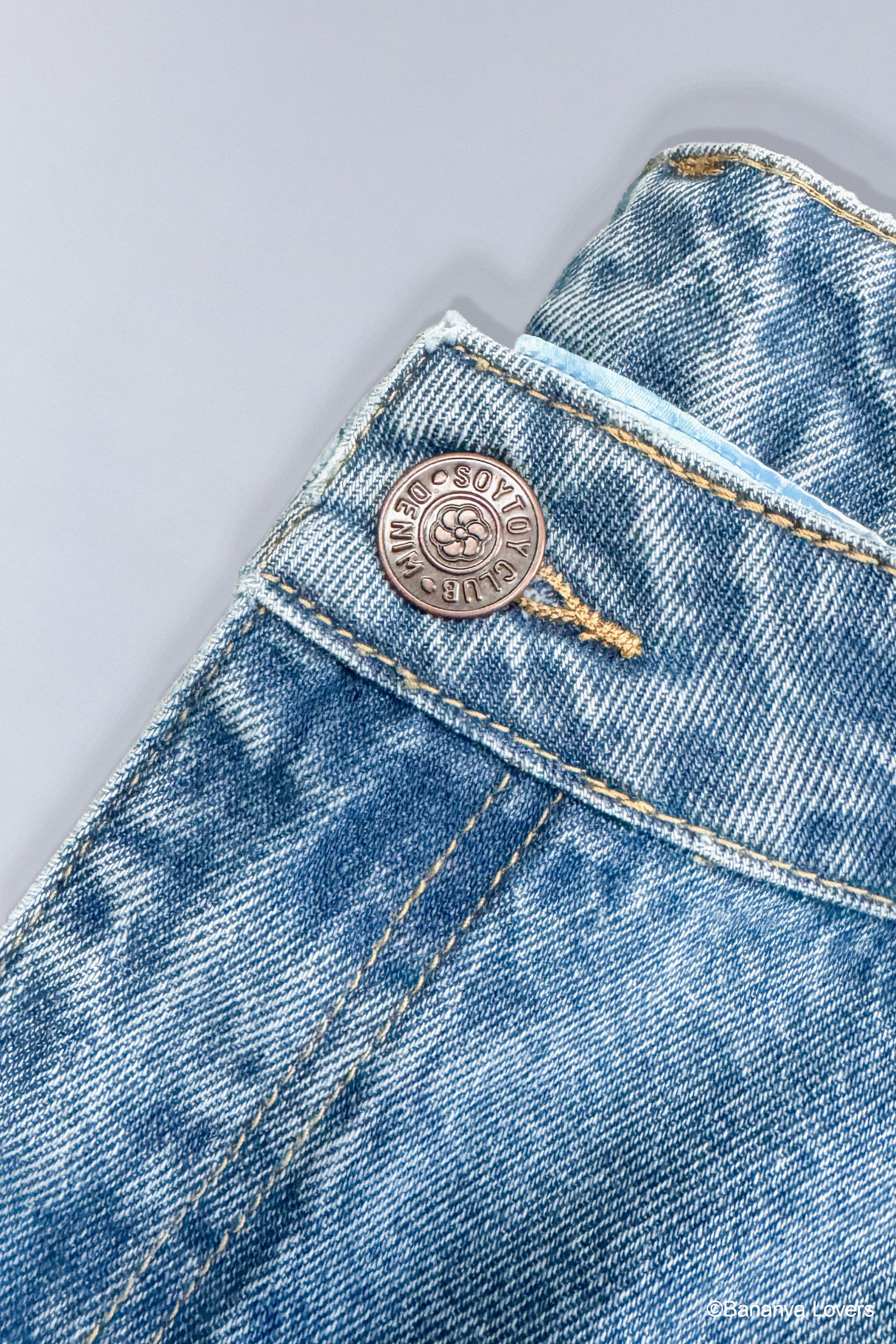 Close up of metal buttons with 'Soytoy Club Denim' branding