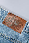 Close up of leather patch on waistline that has embossed Japanese text that reads 'Soytoy Club'