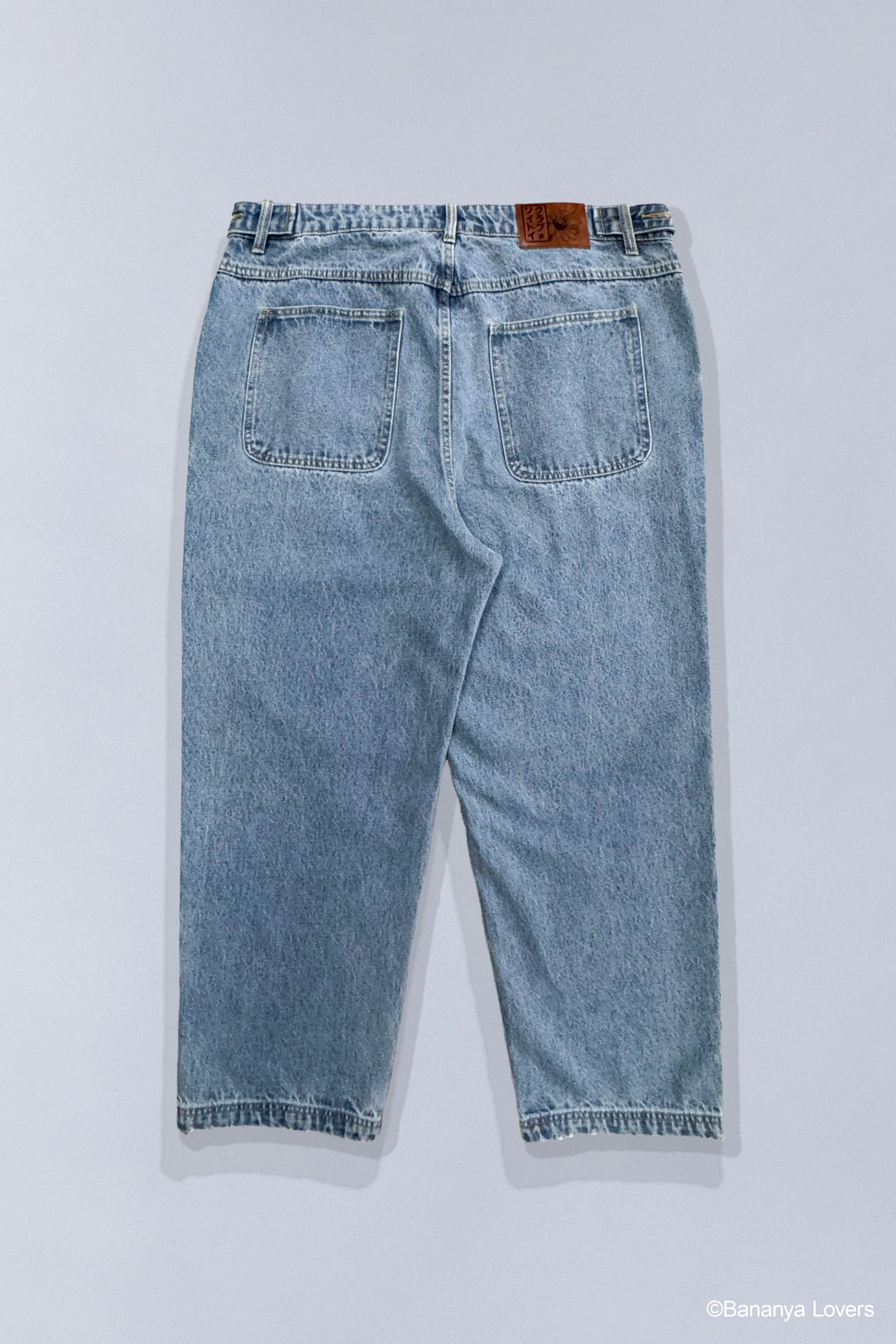 Stone-wash blue jeans that show 3 different Bananya characters stacked on top of each other on bottom left leg