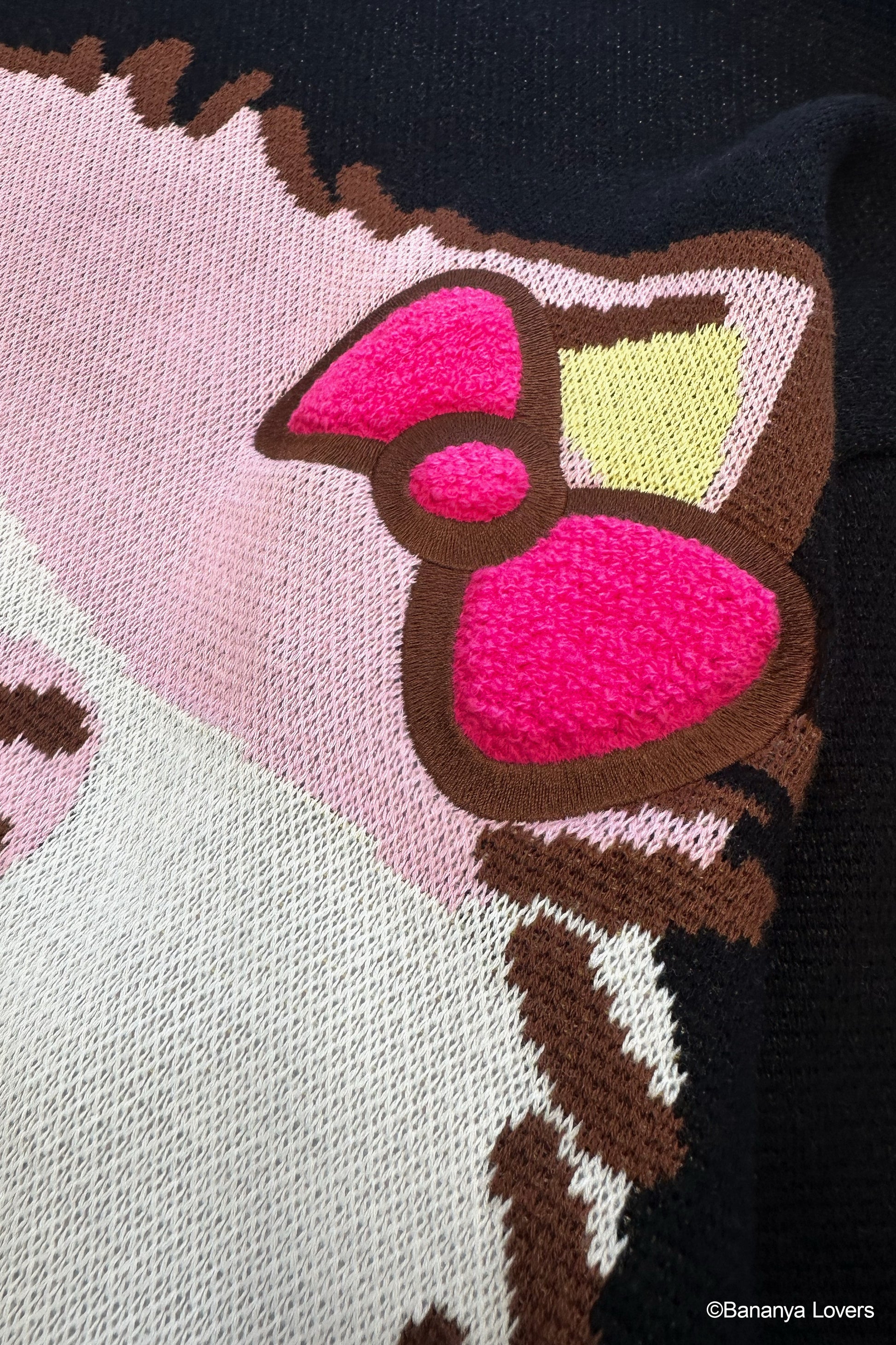 Close up of black knit Bananya sweater. shows raised fluffy bow 