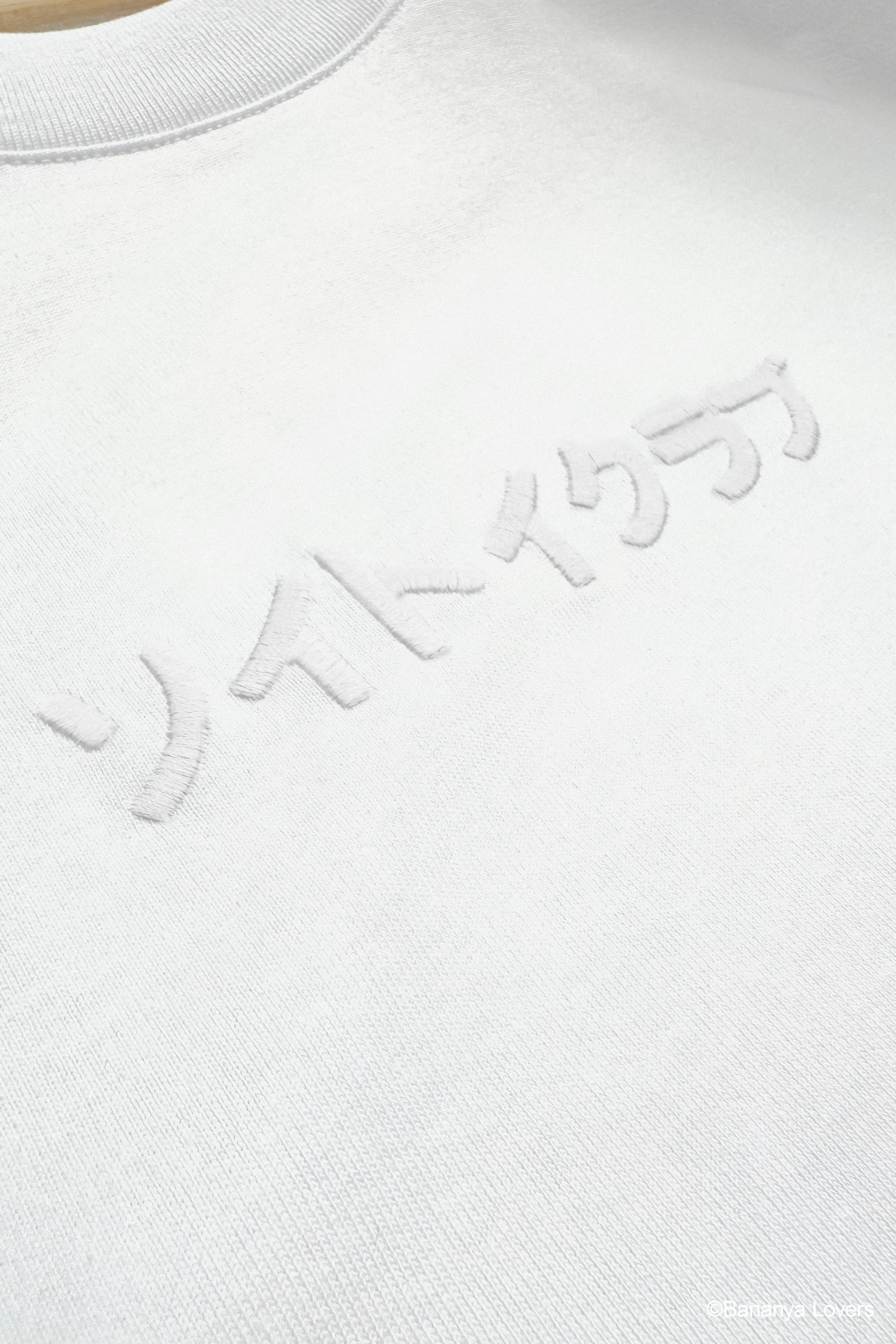 Detail shot of front of white Bananyako t-shirt with embroidered Japanese text that reads 'SOYTOY CLUB'