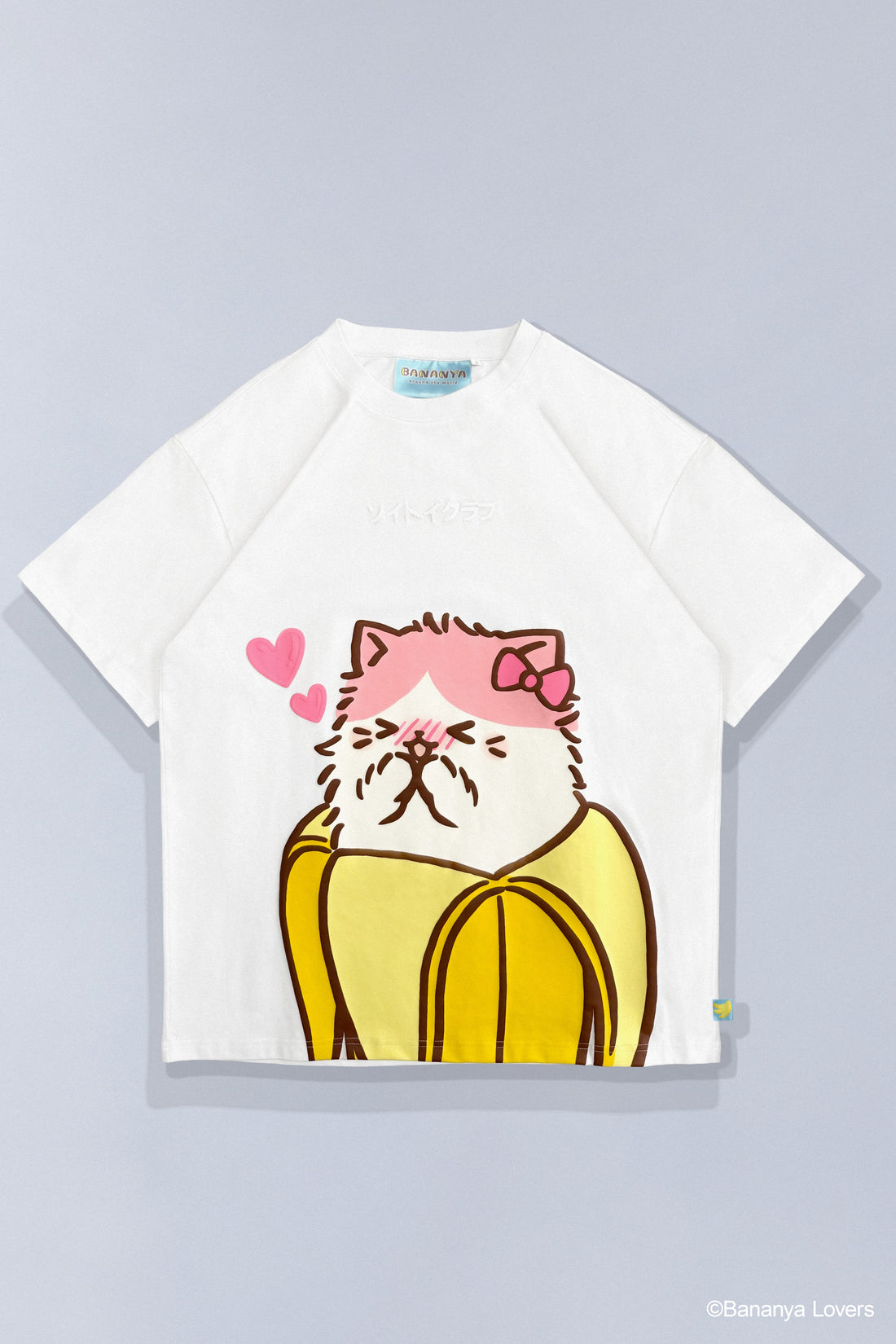 Front of white Bananyako t-shirt. Has large graphic print of Bananyako the white and pink Bananya cat in a yellow banana